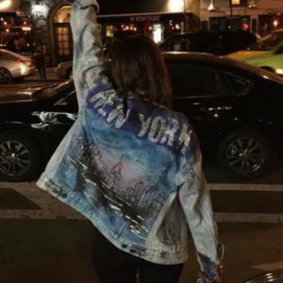 Sara Joy standing in New York City street while wearing a hand painted jean jacket that says New York.