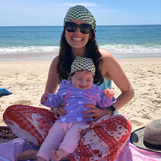 Sara sitting on the beach with her daughter.